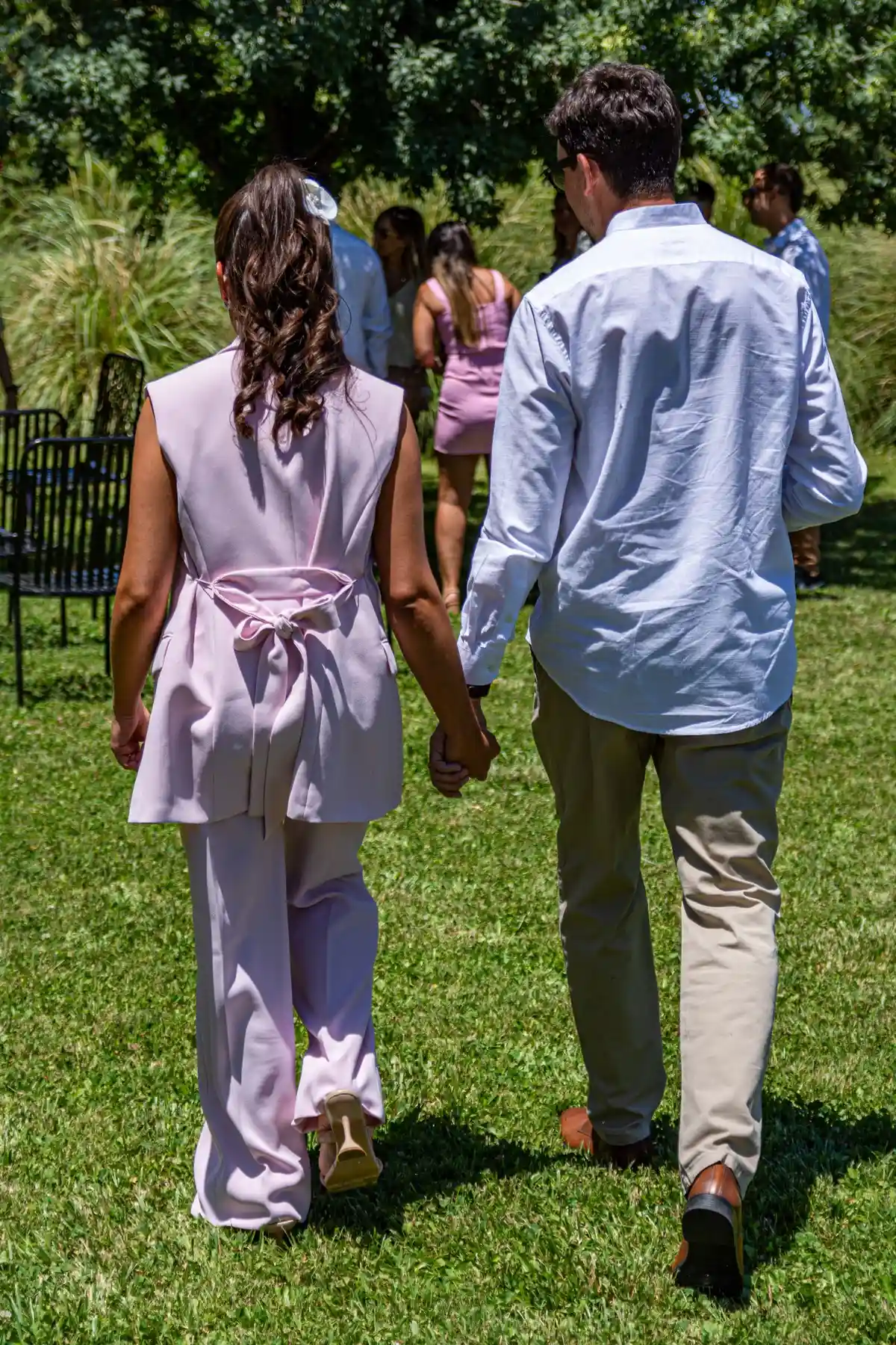 Couple holding hands walking through a sunny garden